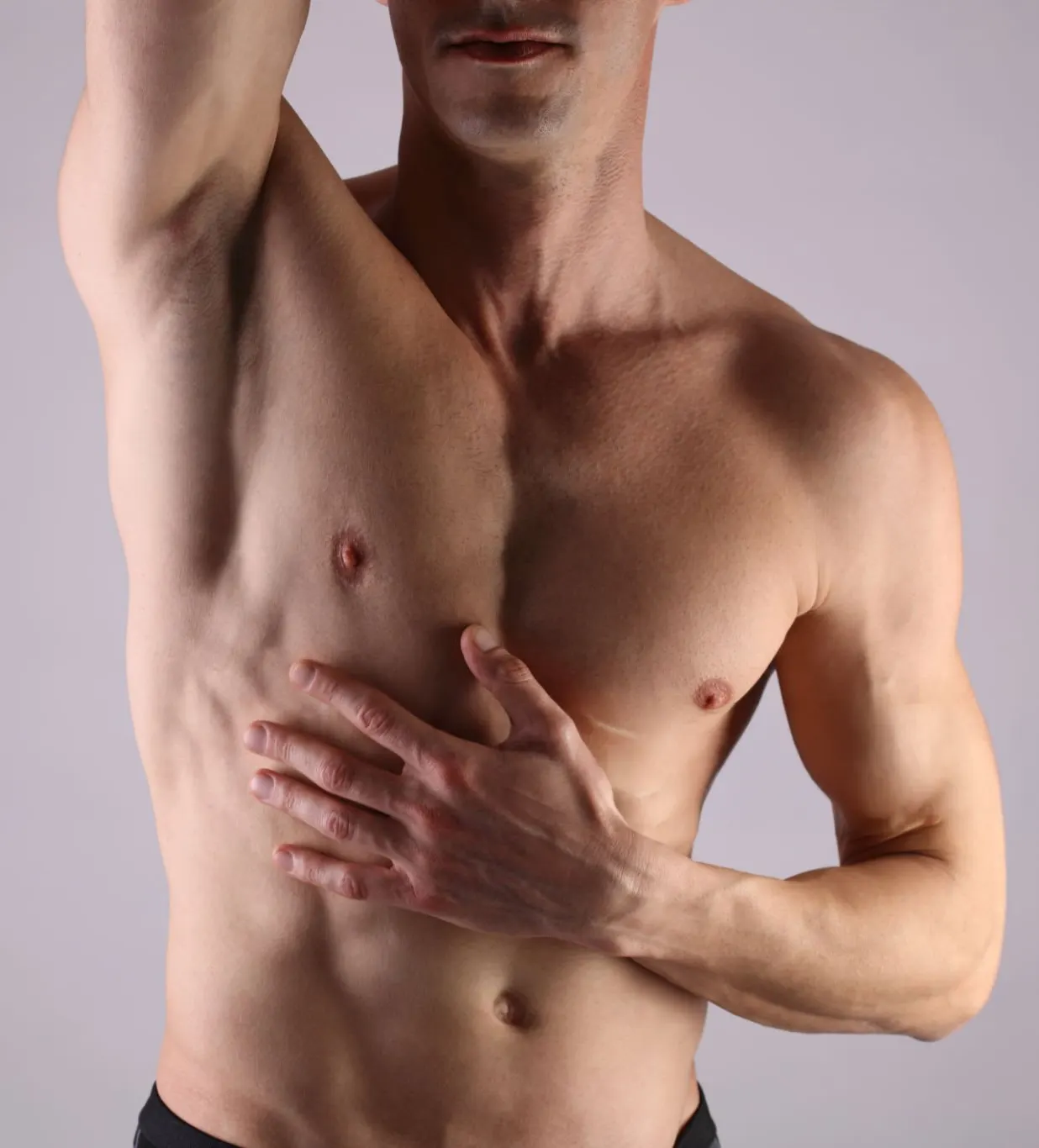 Shirtless man with one arm raised, hand across the chest