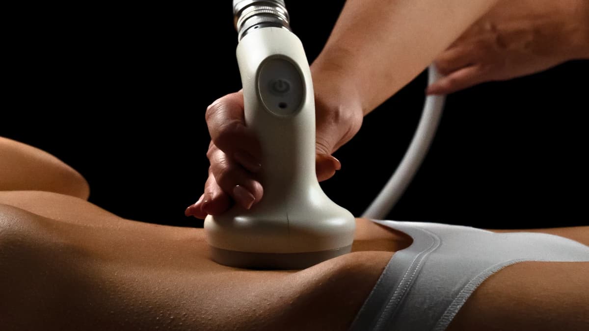 Handheld contouring device pressed to the abdomen during a treatment